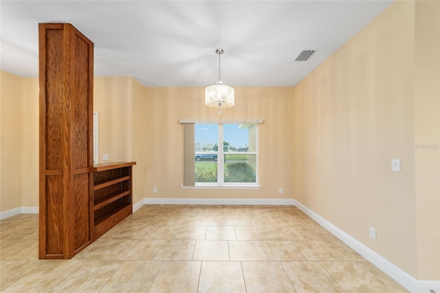 tiled empty room with an inviting chandelier