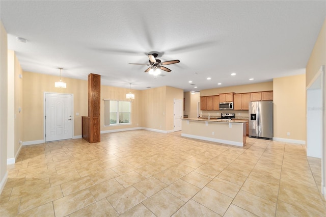 unfurnished living room featuring ceiling fan with notable chandelier, sink, and a textured ceiling