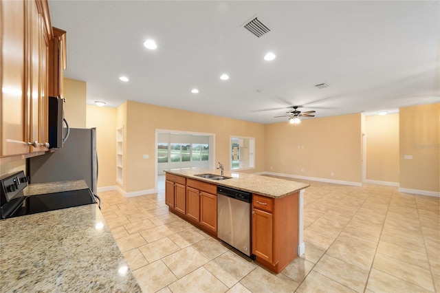 kitchen featuring a center island with sink, stainless steel appliances, sink, ceiling fan, and light stone counters