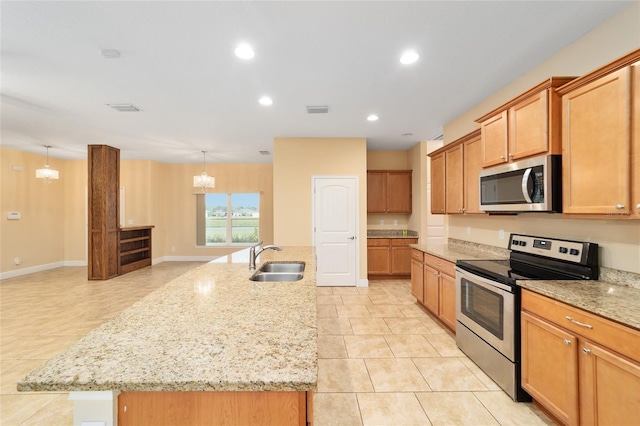 kitchen with a center island with sink, hanging light fixtures, sink, and appliances with stainless steel finishes