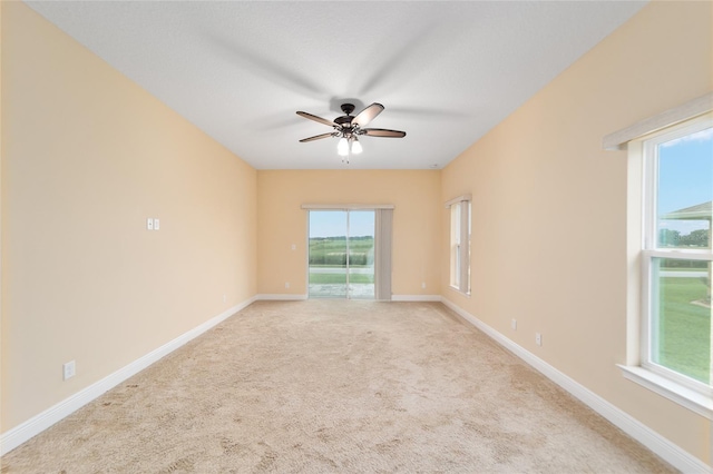 spare room featuring ceiling fan, light carpet, and a healthy amount of sunlight