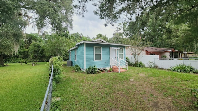 back of property with central AC and a lawn