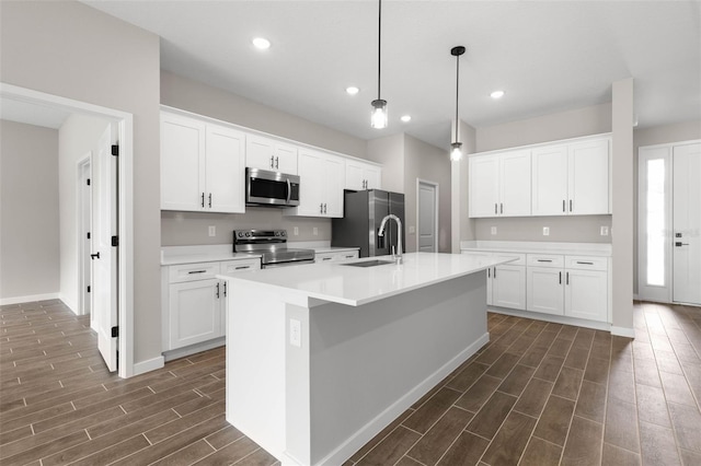 kitchen with sink, stainless steel appliances, pendant lighting, a kitchen island with sink, and white cabinets