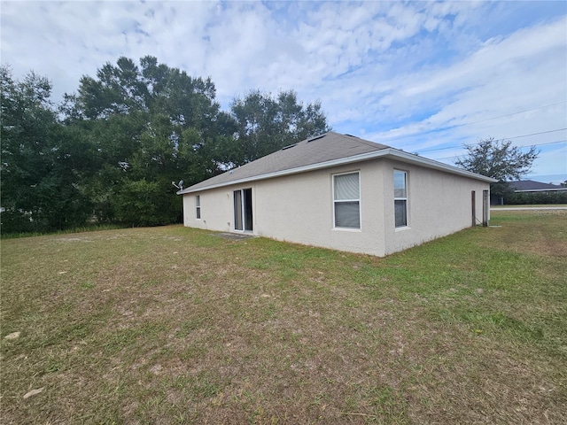 view of side of property with stucco siding and a yard