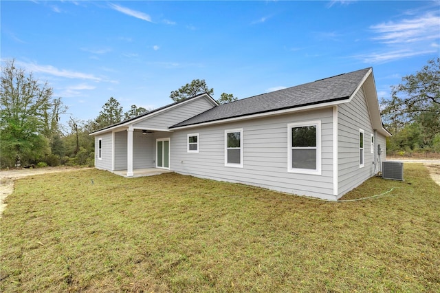 back of house featuring a patio area, a shingled roof, and a lawn