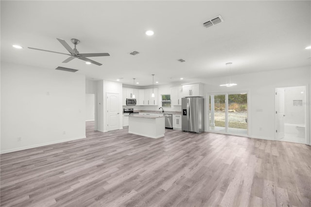 kitchen with appliances with stainless steel finishes, open floor plan, and white cabinets