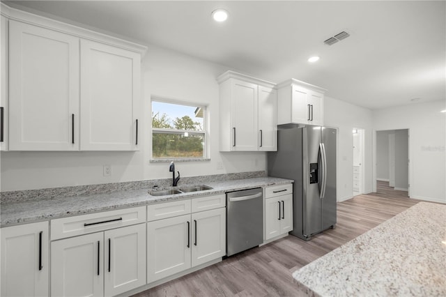 kitchen featuring visible vents, appliances with stainless steel finishes, white cabinets, a sink, and light wood-type flooring