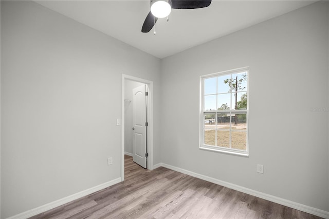 empty room featuring light wood finished floors, baseboards, and a ceiling fan