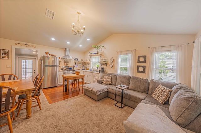 living room with vaulted ceiling, sink, a chandelier, and light hardwood / wood-style floors