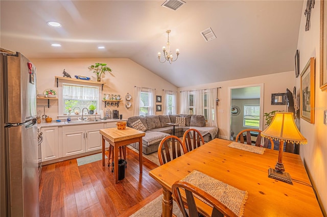 dining area featuring lofted ceiling, an inviting chandelier, sink, and hardwood / wood-style flooring