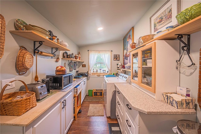 kitchen featuring vaulted ceiling, white cabinetry, washing machine and clothes dryer, and dark wood-type flooring