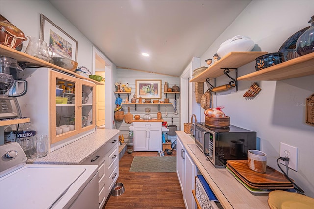 interior space with washer / dryer, dark hardwood / wood-style floors, white cabinetry, and vaulted ceiling