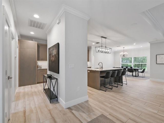 interior space with light wood-type flooring, a chandelier, crown molding, and sink