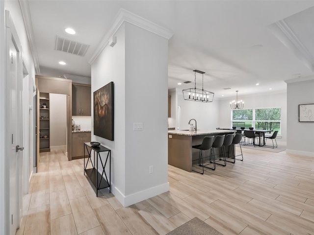 interior space featuring light wood-type flooring, a chandelier, crown molding, and sink