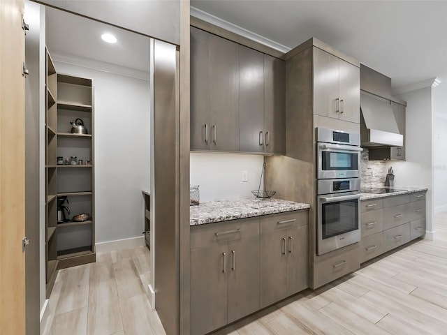 kitchen featuring black electric stovetop, crown molding, stainless steel double oven, light hardwood / wood-style flooring, and light stone countertops