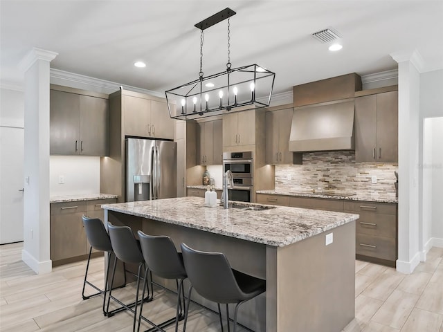 kitchen featuring a center island with sink, a breakfast bar, light stone countertops, and appliances with stainless steel finishes