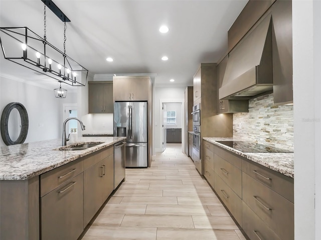 kitchen featuring custom range hood, light stone countertops, appliances with stainless steel finishes, sink, and pendant lighting