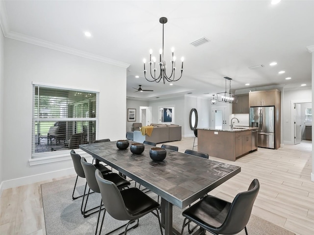 dining space featuring ceiling fan, ornamental molding, sink, and light hardwood / wood-style floors