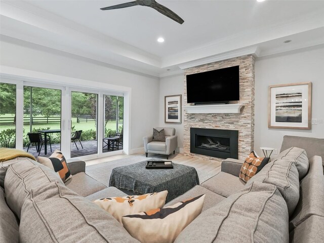 living room featuring a tray ceiling, recessed lighting, a fireplace, baseboards, and ceiling fan