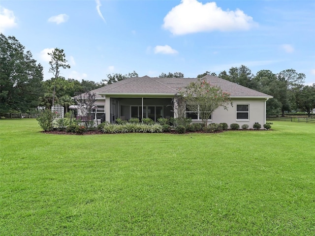 back of house with a yard, a sunroom, and stucco siding