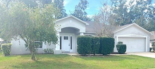 ranch-style home featuring a garage and a front lawn