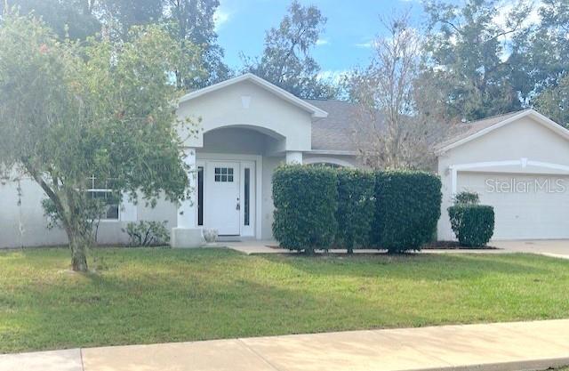 2712 NE 26th St, Ocala, FL 34470 - ranch-style house featuring a front lawn, stucco siding, an attached garage, and driveway