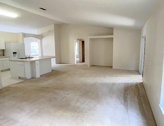 unfurnished living room featuring light carpet and vaulted ceiling