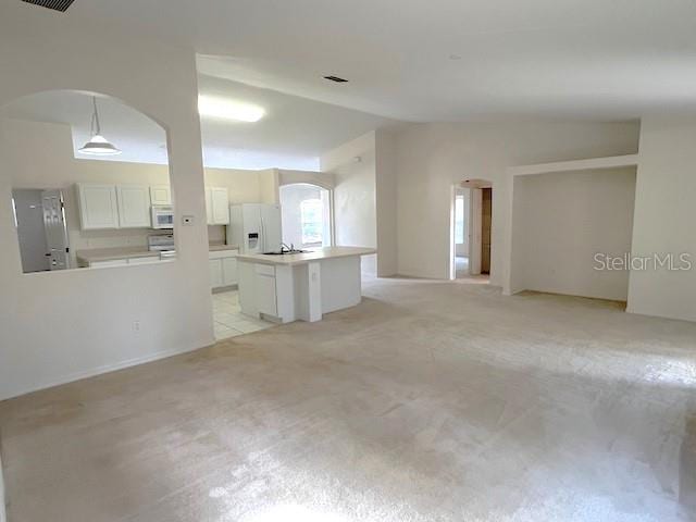 unfurnished living room with light colored carpet and vaulted ceiling