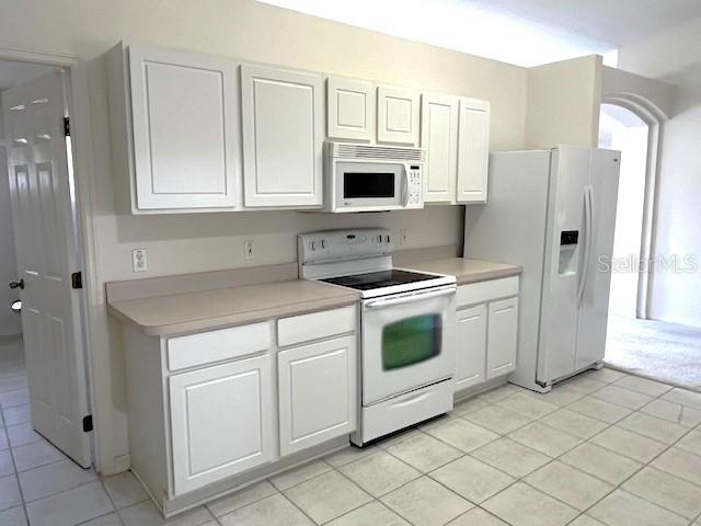 kitchen with white cabinets, light tile patterned floors, and white appliances