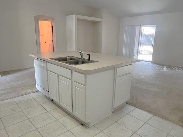 kitchen featuring sink, a kitchen island with sink, white dishwasher, light carpet, and white cabinets