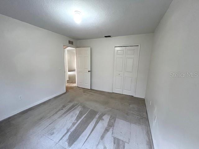 unfurnished bedroom featuring a textured ceiling and a closet