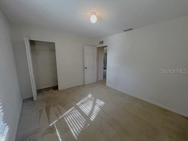 unfurnished bedroom featuring light carpet and a closet