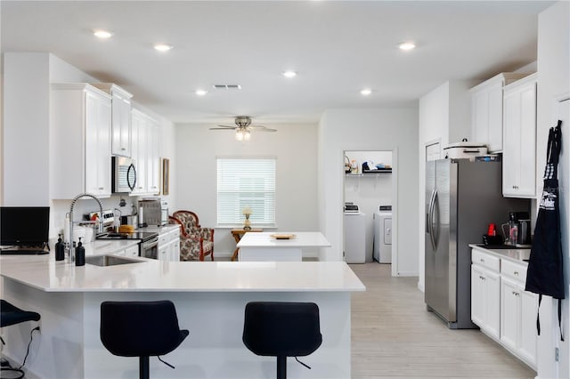 kitchen featuring visible vents, a sink, a kitchen island, appliances with stainless steel finishes, and a peninsula