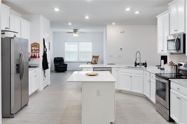 kitchen featuring white cabinets, appliances with stainless steel finishes, a kitchen island, and sink