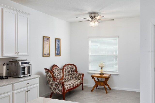 living area with a wealth of natural light, light hardwood / wood-style floors, and ceiling fan