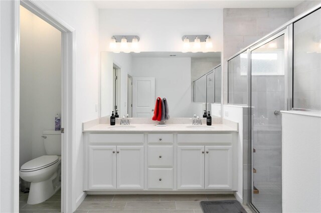 bathroom featuring tile patterned flooring, vanity, toilet, and an enclosed shower