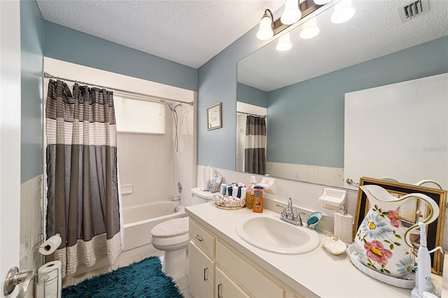 full bathroom with a textured ceiling, vanity, shower / tub combo with curtain, toilet, and tile patterned floors