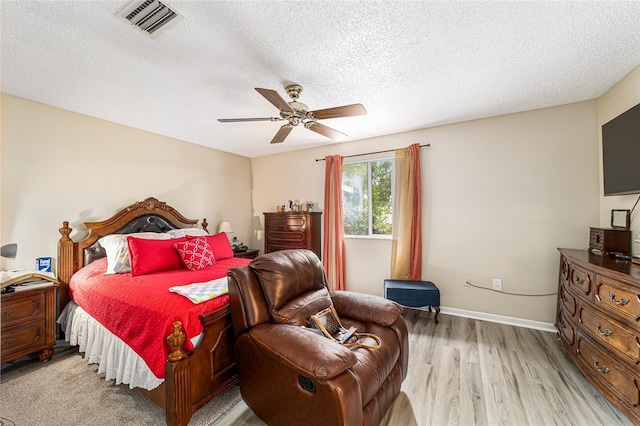 bedroom with light wood-type flooring, ceiling fan, and a textured ceiling