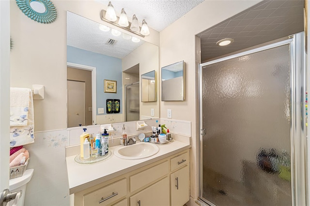 bathroom with vanity, tile walls, toilet, and a shower with shower door