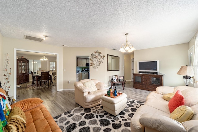 living room featuring a textured ceiling, hardwood / wood-style flooring, and an inviting chandelier