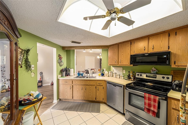 kitchen featuring light wood-type flooring, a textured ceiling, stainless steel appliances, sink, and ceiling fan