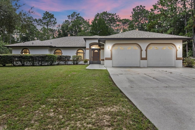 ranch-style home with a garage and a yard