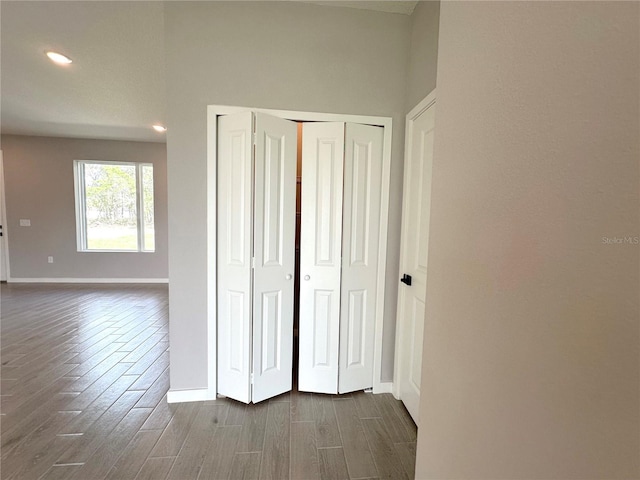 unfurnished bedroom with a closet, baseboards, and dark wood-style flooring