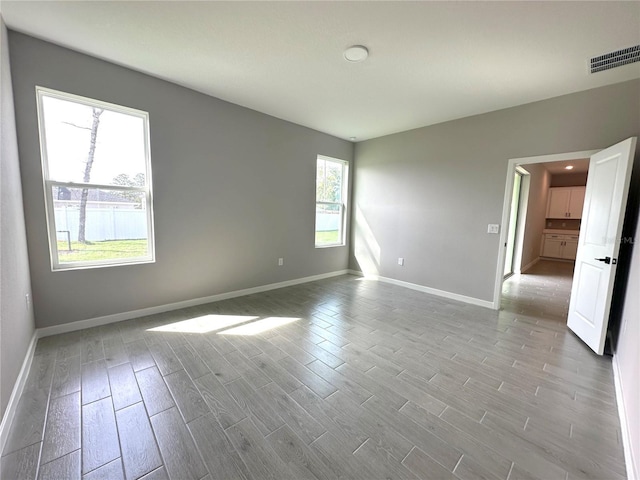 spare room featuring baseboards, visible vents, and wood finished floors