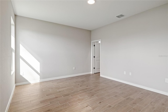 spare room with baseboards, visible vents, and light wood finished floors