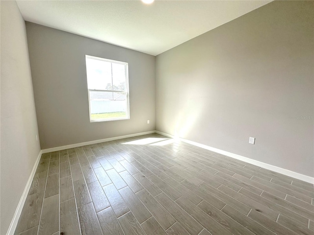 spare room featuring wood finish floors and baseboards