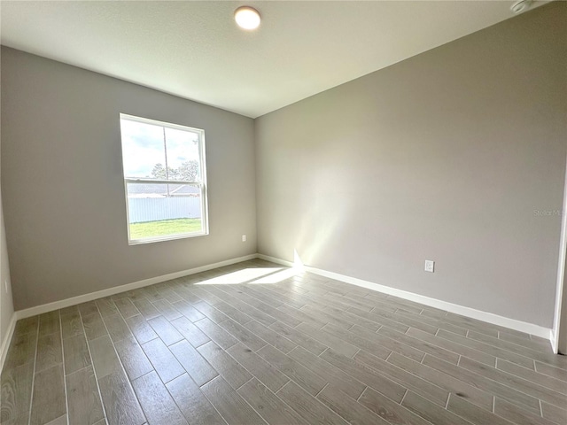 unfurnished room with dark wood-style flooring and baseboards