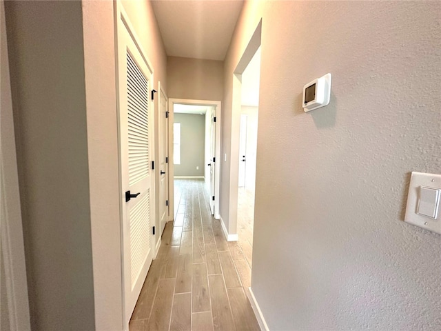 corridor with wood finish floors and baseboards