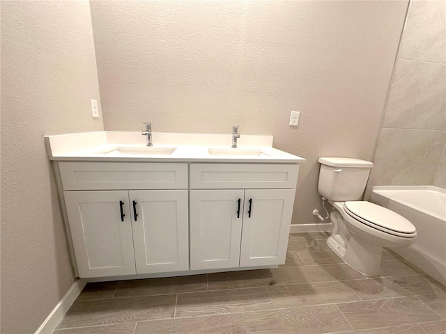 full bathroom with double vanity, a sink, toilet, and baseboards