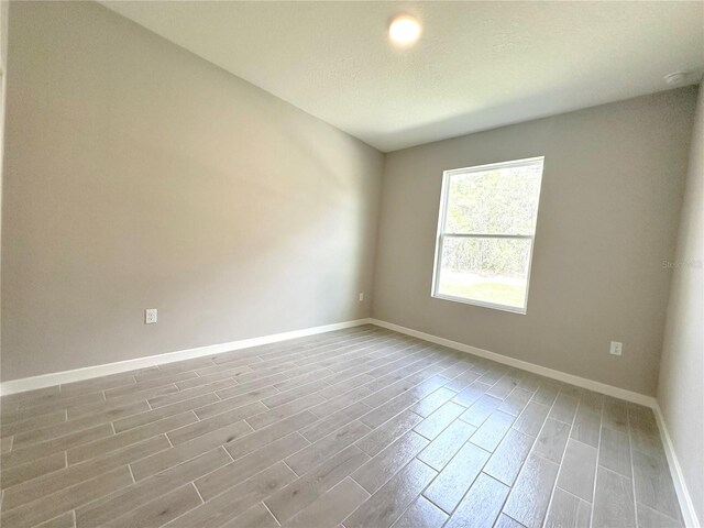 empty room featuring baseboards and wood finish floors